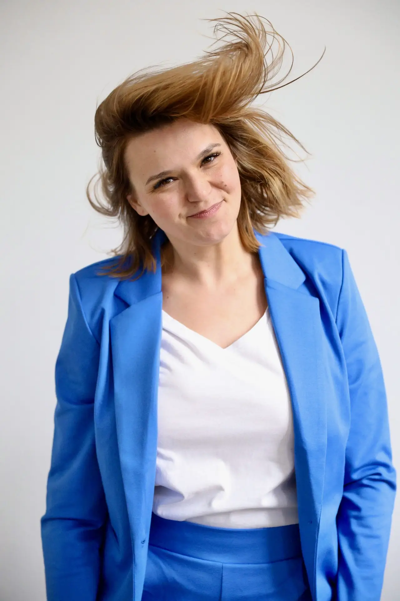 Die Hamburger Präventionsmanagerin Nora Remstedt lächelt entspannt in einem blauen Anzug; eine lockere Atmosphäre, die für erfolgreiche Burnout-Prävention steht.
