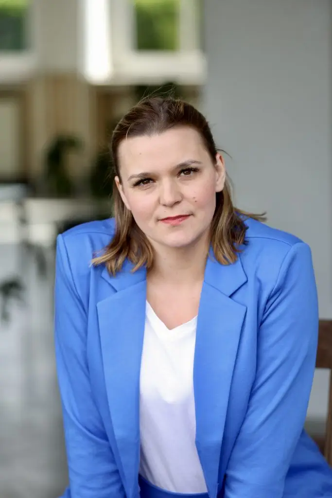 Systemische Beraterin für Stressbewältigung Nora Remstedt schaut aufmerksam und offen in die Kamera und trägt einen blauen Blazer und ein weißes Shirt der Hintergrund ist leicht verschwommen.