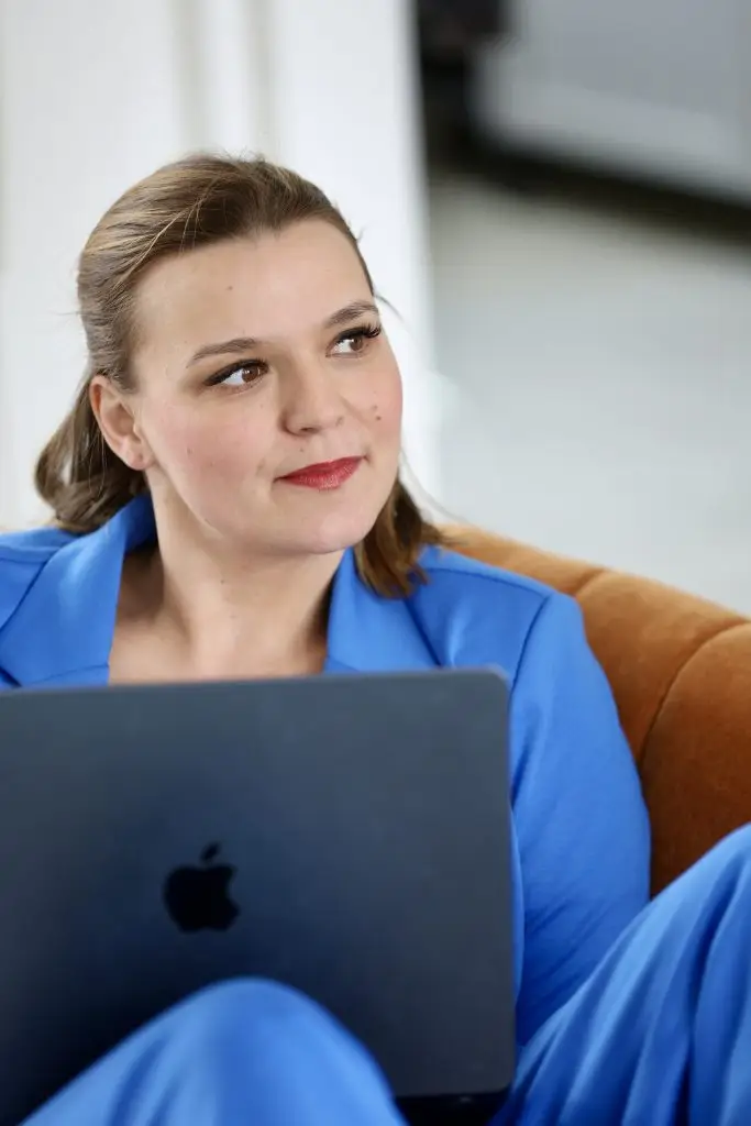 Nora Remstedt Systemische bEraterin am Laptop lächelt leicht und dnekt nach