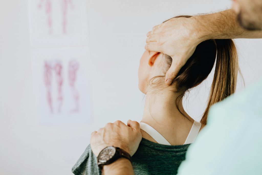 Der Kopf von einer Frau Wird zur Seite dedehnt, eine Hand auf der Schulter eine an der Schläfe, ein Sysmbolbild für Nackenverspannung durch Stress
